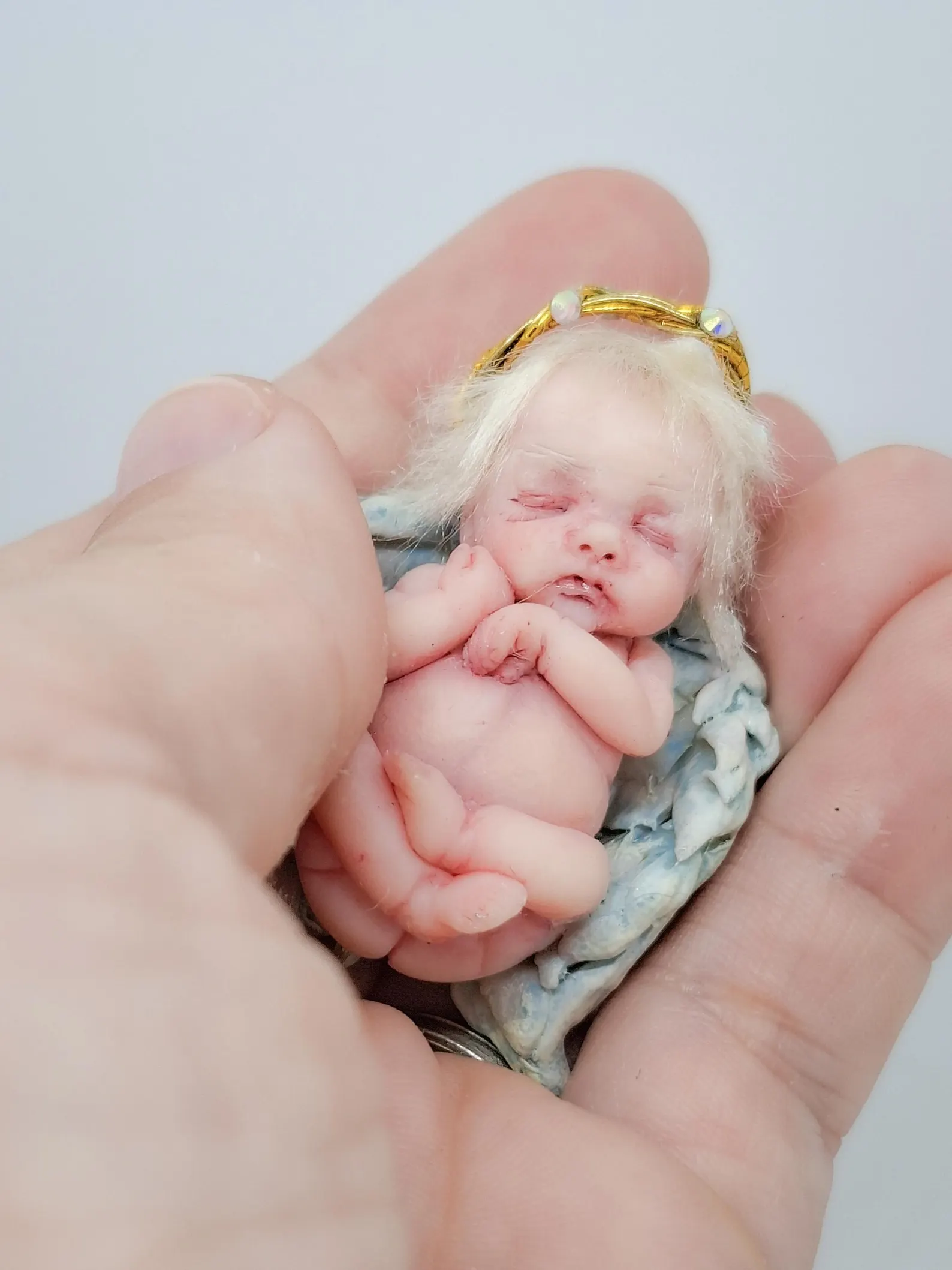 OOAK miniature angel art doll titled The Light Bearer, a handmade polymer clay sculpture with ethereal wings, part of the Divine Collection.