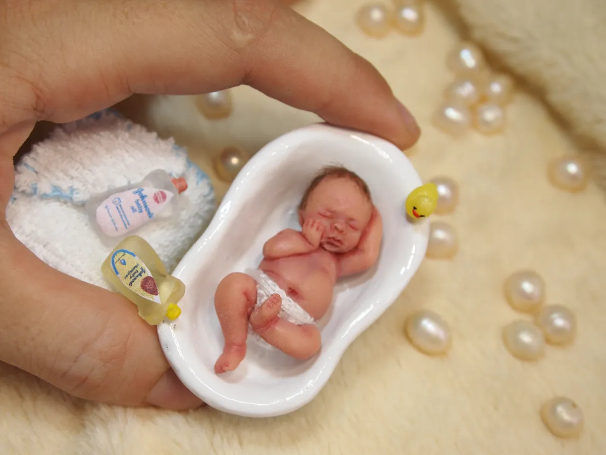 Whimsical OOAK miniature baby doll in tiny white ceramic bathtub with miniature toiletries including soap and shampoo bottles - by Mini Baby Dolls