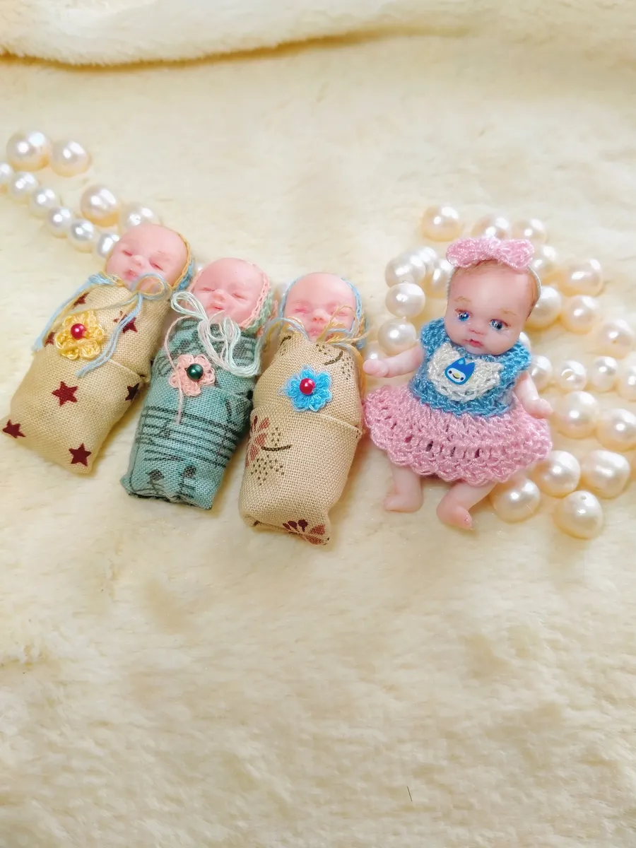 Three OOAK miniature baby dolls wrapped in burlap sacks displayed in a row with pearl beads, showcasing variety of skin tones - by Mini Baby Dolls