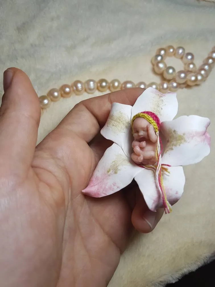 Ethereal OOAK miniature baby doll sleeping inside a white orchid flower, a whimsical nature-inspired display - by Mini Baby Dolls