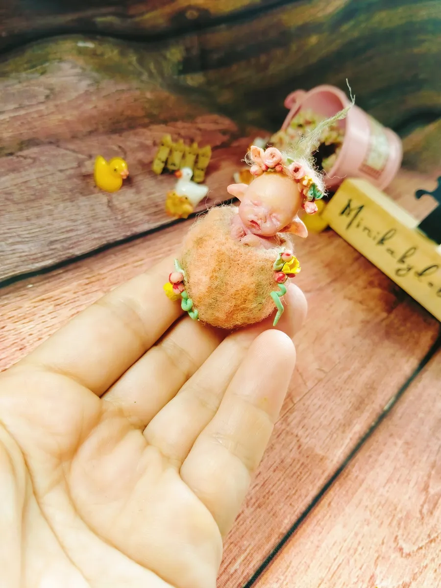 Enchanting OOAK miniature fairy baby doll with delicate wings and flower crown, standing on felt moss ball in palm - by Mini Baby Dolls