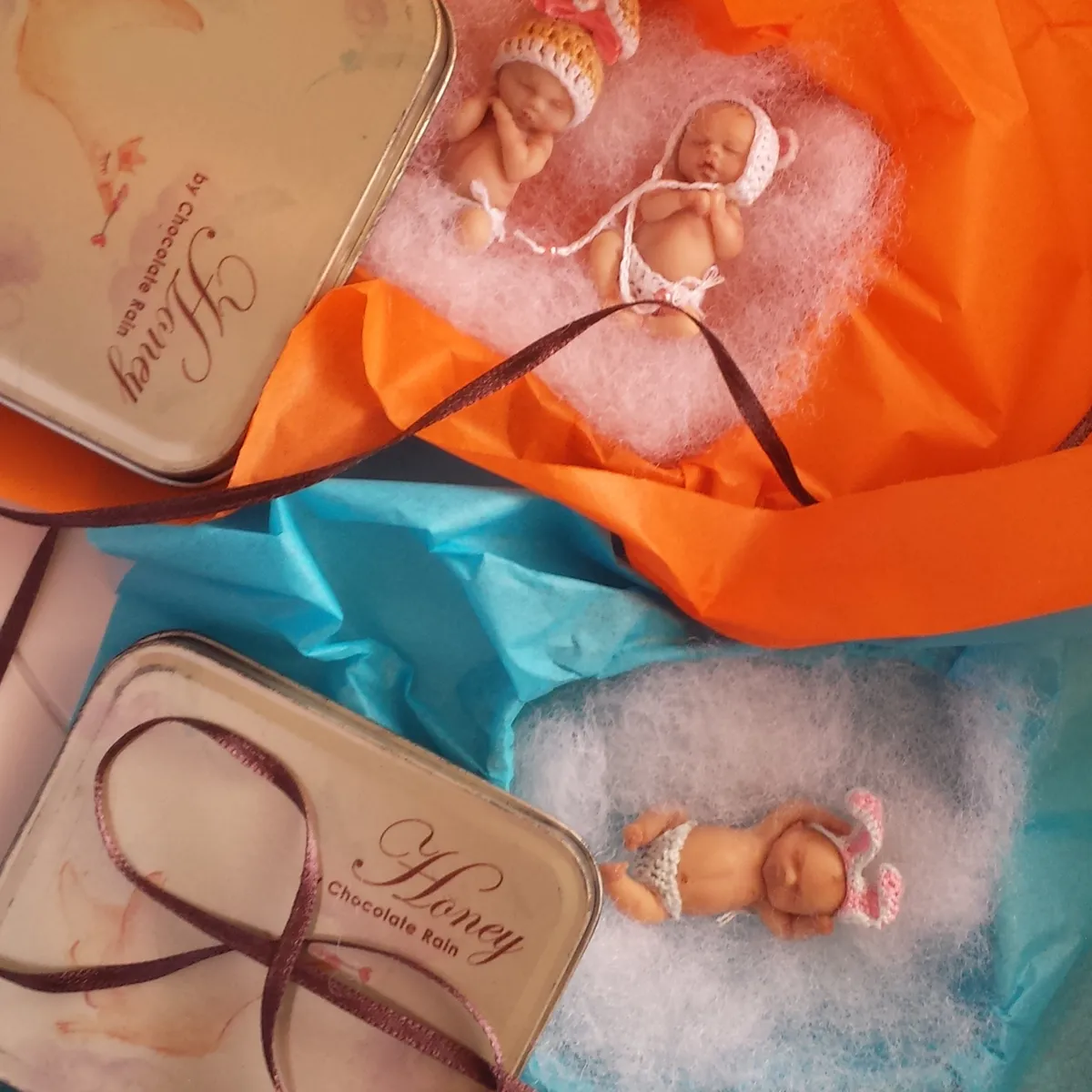 Two beautifully packaged OOAK miniature baby dolls - one on pink bed in gift box, one in 'Honey' labeled vintage tin - by Mini Baby Dolls