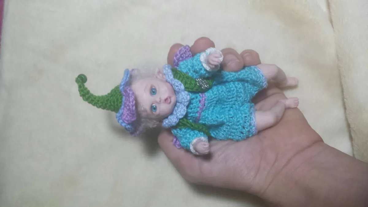 Whimsical OOAK miniature mermaid baby doll in blue crocheted tail costume with matching elf hat, held in palm - by Mini Baby Dolls