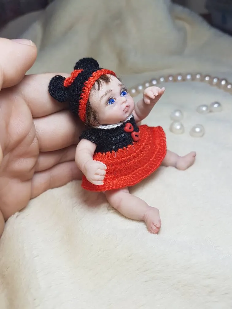 Adorable OOAK miniature baby doll in red Minnie Mouse inspired dress with black mouse ears and red bow, posing playfully in palm - by Mini Baby Dolls