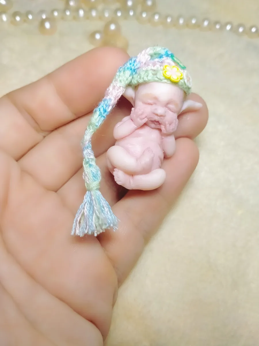 Sleeping OOAK miniature baby doll in colorful pastel crocheted hanging bassinet/cradle with tassel, held in palm - by Mini Baby Dolls