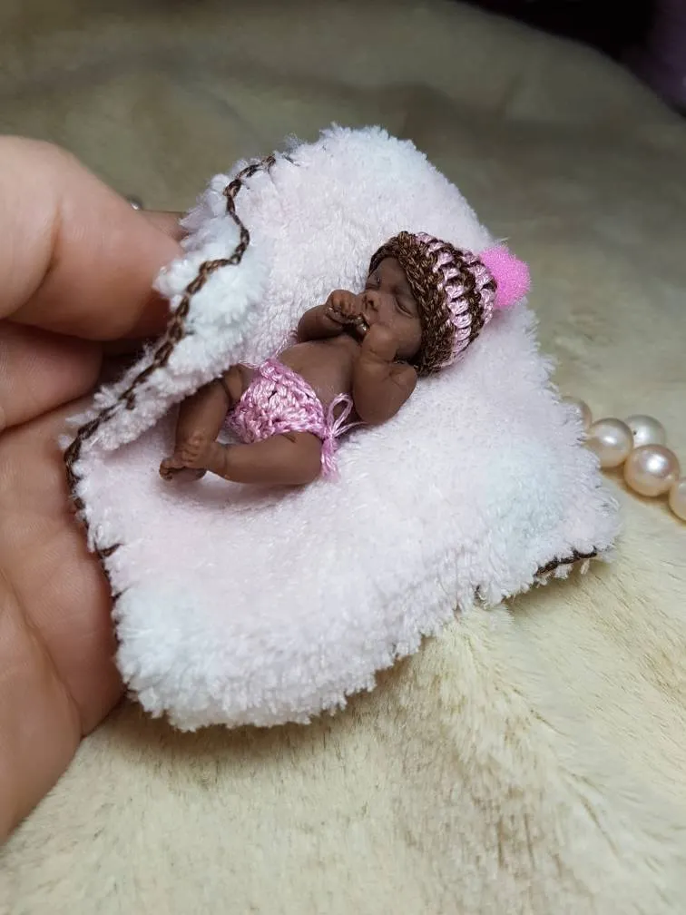Sleeping OOAK miniature baby doll with brown braided hair and pink crocheted outfit, resting on fluffy white pillow - by Mini Baby Dolls