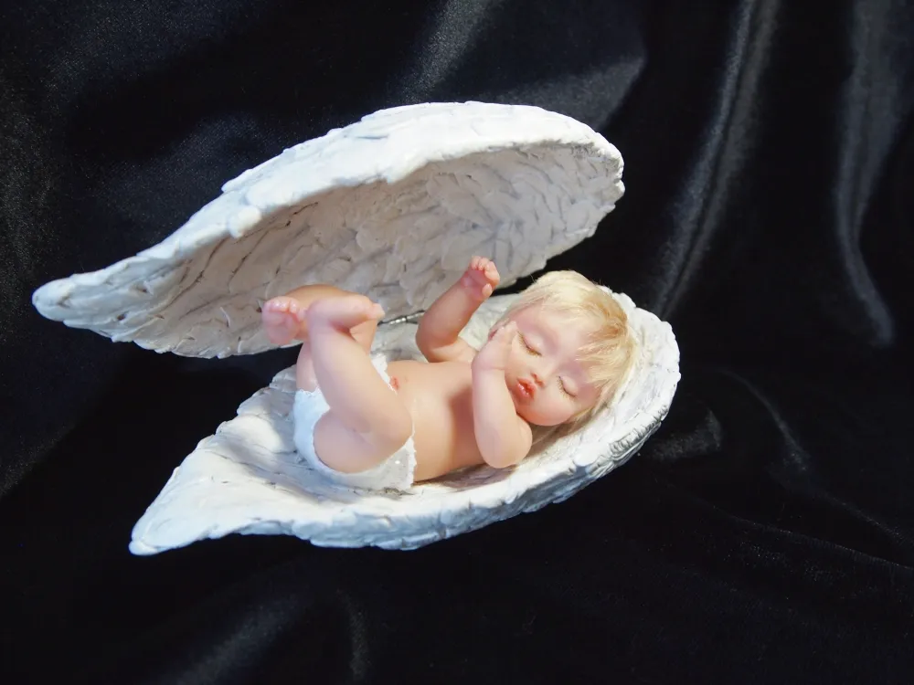 Ethereal sleeping OOAK miniature baby doll nestled inside a sculpted white seashell or angel wing, displayed on elegant black velvet background - by Mini Baby Dolls