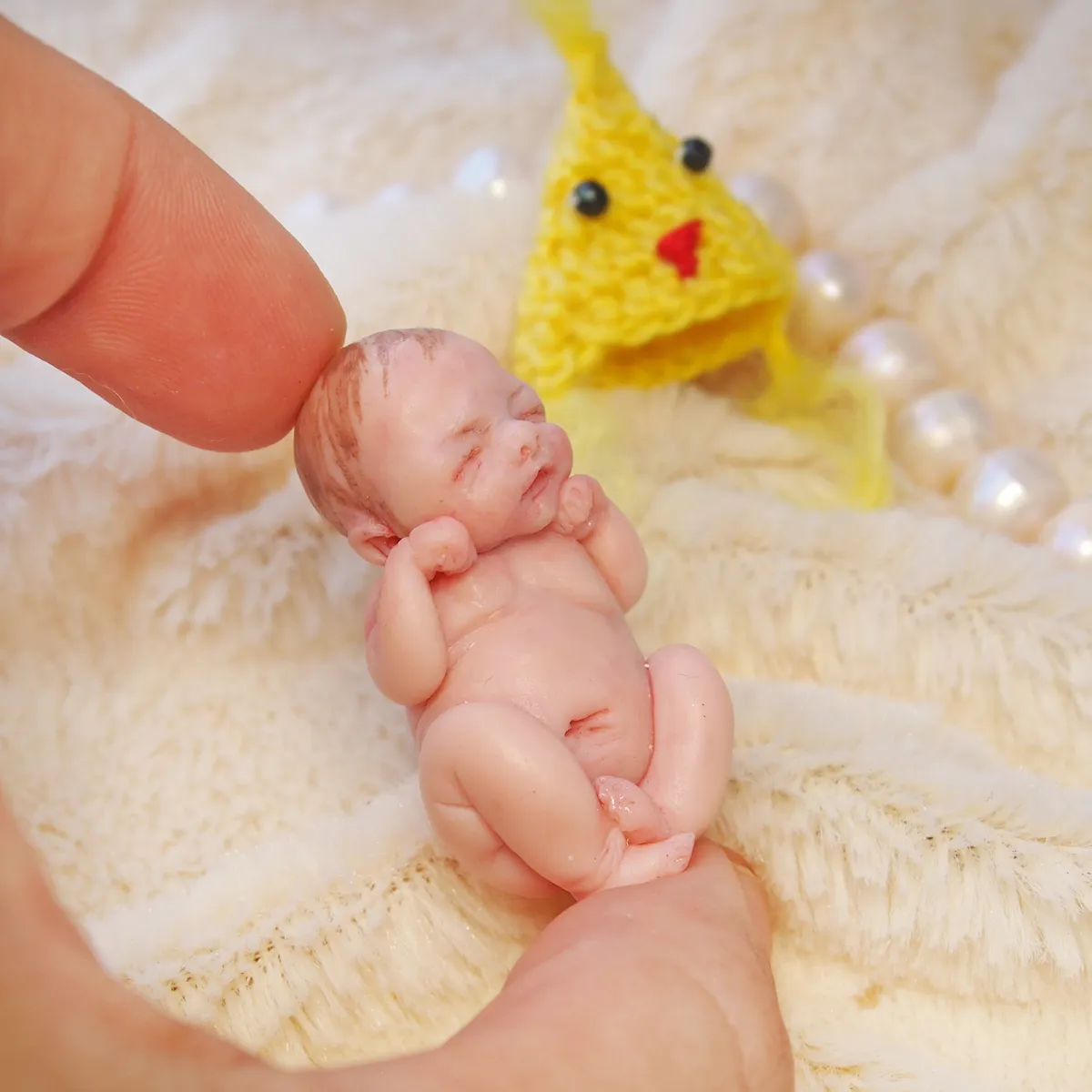 Peaceful sleeping OOAK miniature baby doll with a handmade yellow crocheted baby chick companion, displayed on soft cream fabric with pearl beads - by Mini Baby Dolls