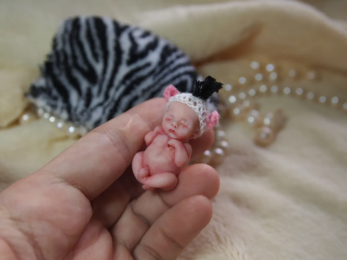 Sleeping OOAK miniature baby doll displayed on zebra print fabric, held in palm with pearl beads - by Mini Baby Dolls