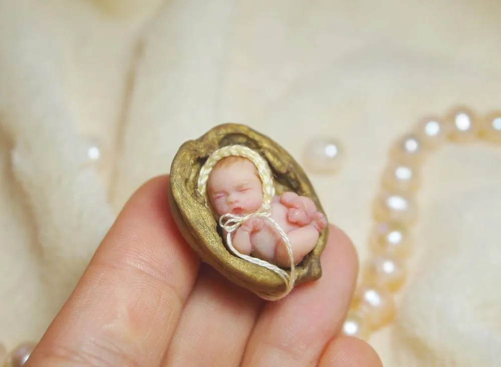 Standing OOAK miniature baby doll with red-ginger hair, wearing colorful rainbow crocheted bloomers, displayed in palm with pearl beads - by Mini Baby Dolls