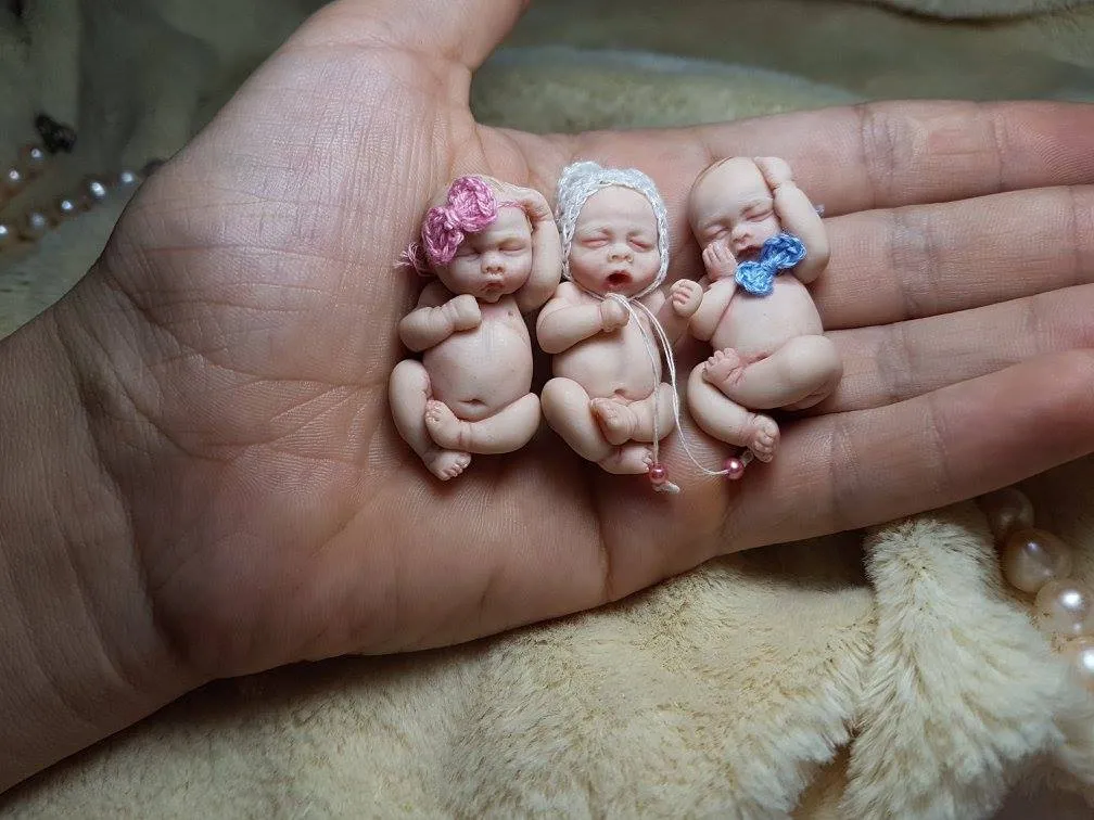 Three adorable OOAK miniature baby dolls together in palm, one wearing a delicate pink flower headband, showcasing variety - by Mini Baby Dolls