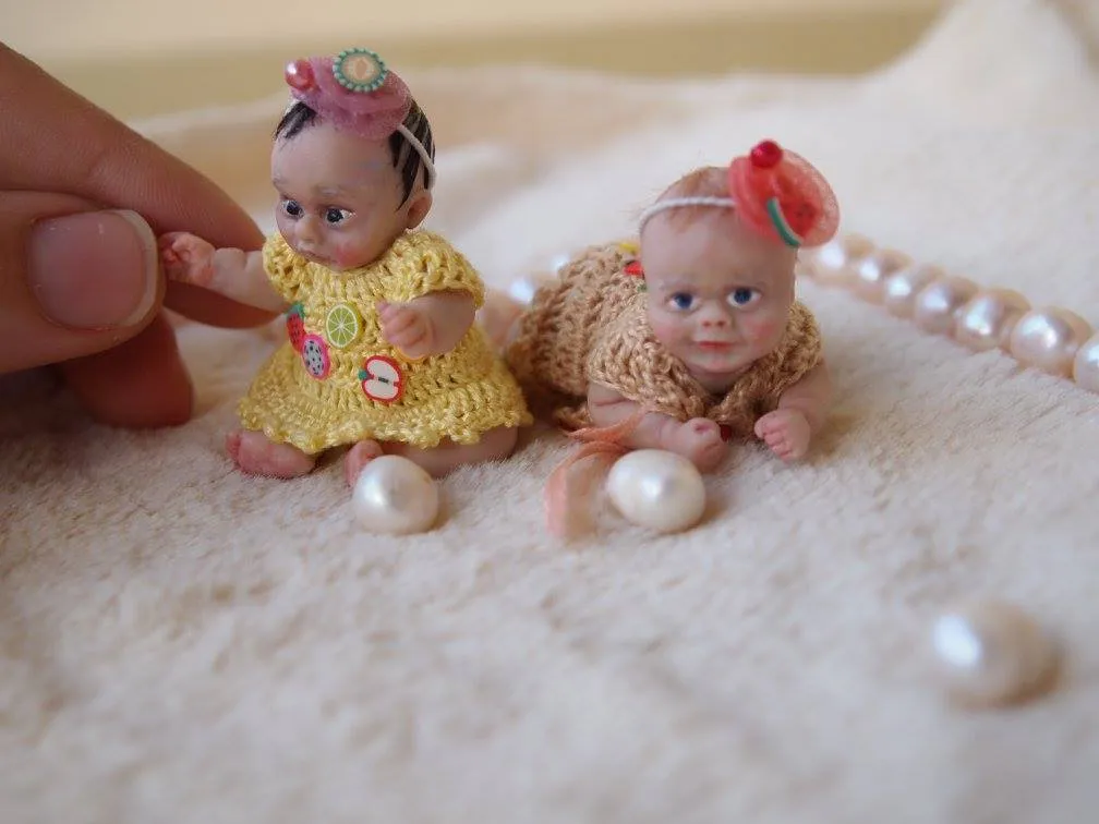 Two cheerful OOAK miniature baby dolls in matching yellow crocheted dresses with red flower headbands, displayed with pearl beads - by Mini Baby Dolls