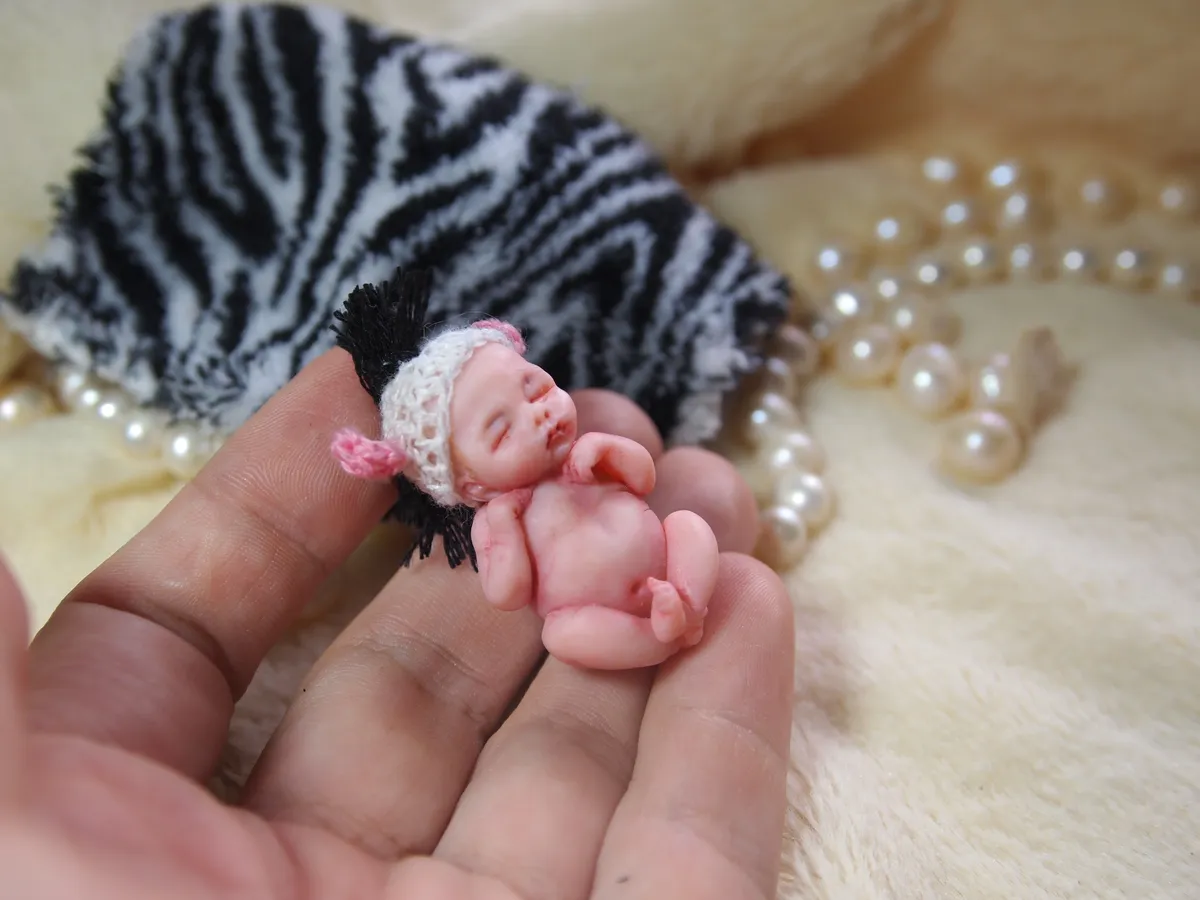 Sleeping OOAK miniature baby doll in white crocheted bonnet, displayed on zebra print fabric with pearl beads - by Mini Baby Dolls