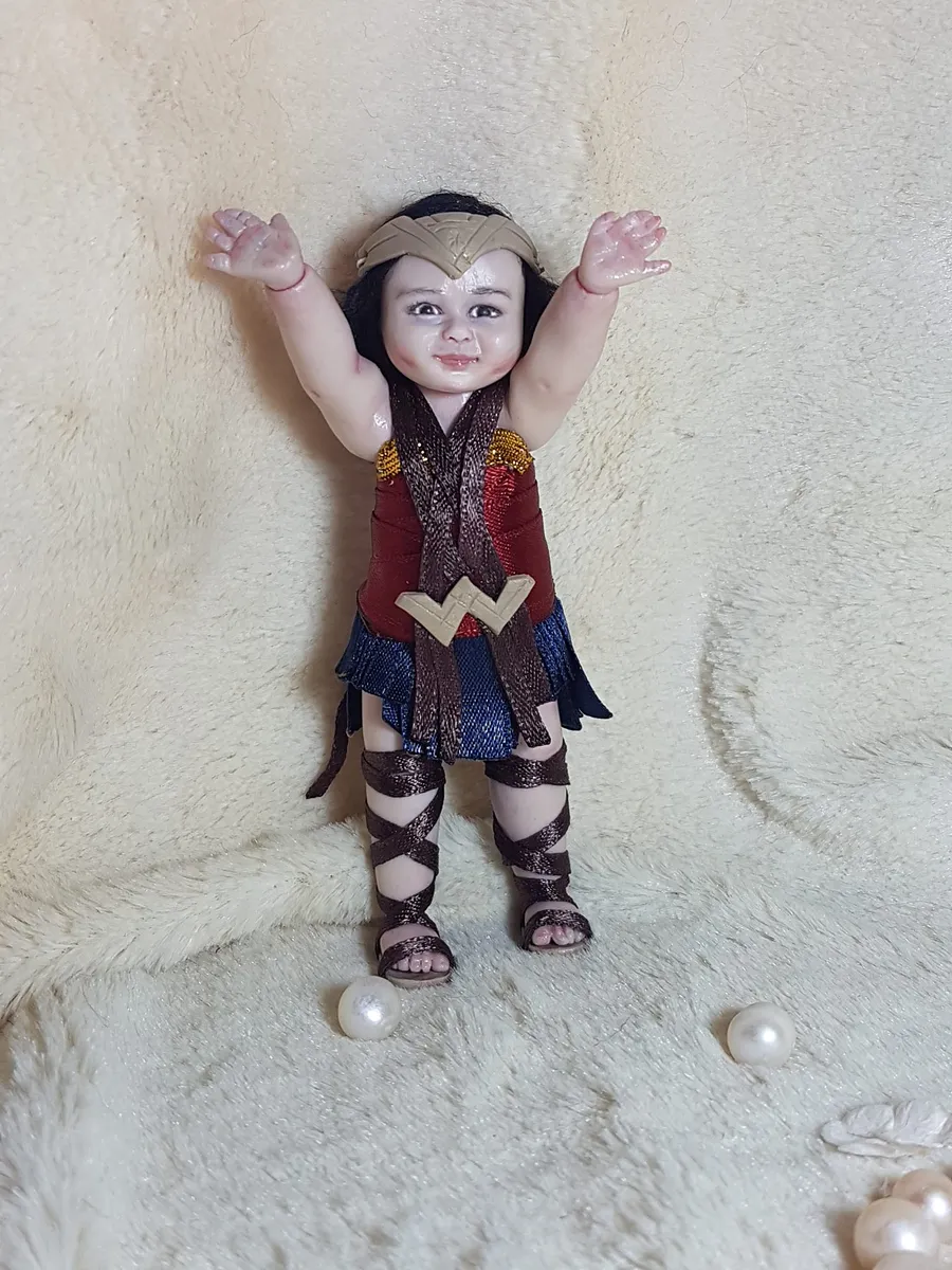 Detailed OOAK miniature Wonder Woman toddler doll in full superhero costume with tiara, bracelets and lasso, arms raised victoriously - by Mini Baby Dolls